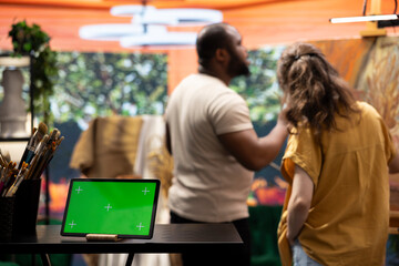 In a creative atelier, painters use colorful paint tubes and brushes to create a masterpiece next to copy space display. Team of artists working on a nature inspired painting.