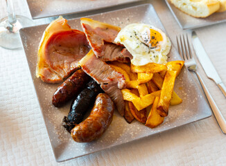 Close up of tasty fried pork with assorted Spanish sausages and potatoes