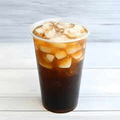 Iced brown sugar milk tea with ice cubes in a clear plastic cup on a wooden table. Perfect for drink menu or beverage ads