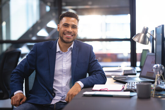 Man sitting at modern office desk, using laptop showing chart with clipboard, mug and desk lamp