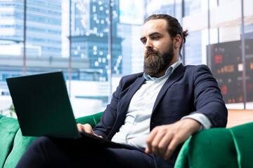 Ambitious male CEO working in a modern luxurious skyscraper, reviewing financial forecasts and...