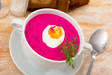 Traditional Belarusian cold vegetable soup Holodnik with beetroot and egg on chekered tablecloth