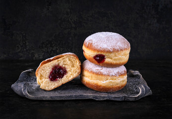 Authentic traditional German festive Berliner Krapfen - jam doughnut with icing sugar as close-up o a design tray