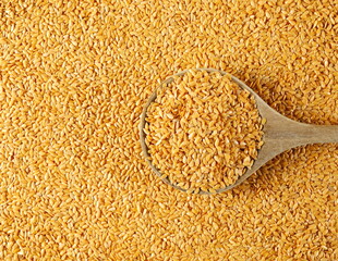 Organic golden flax seeds, linseed grains in wooden spoon background and texture