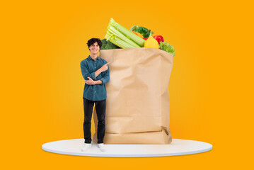 A customer stands beside an oversized paper bag brimming with various vegetables and fruits, showcasing the joy of grocery shopping amidst changing shopping habits in a bright, isolated setting.