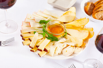 Plate with different types of cheese and a cup of honey