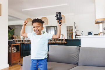 boy child celebrating game victory in open living room, holding video game controller