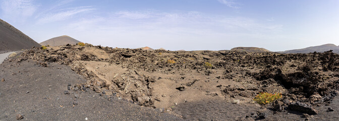 Panoramic landscape of Lanzarote with volcanic terrain and a clear sky, showcasing the island's unique geological features.
