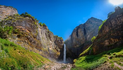 Obraz premium waterfall into deep gorge rocky cliffs under blue sky