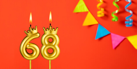 Number 68 birthday candle on an orange background with pennants