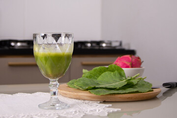 mesa da cozinha com copo de suco verde e ingredientes orgânicos e saudáveis