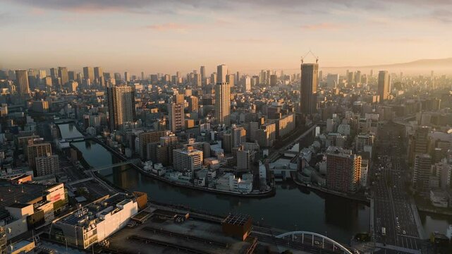 osaka city central minami ward aerial view drone at sunrise,flying over kizu river,high-rise office buildings in the background,metropolis cityscape