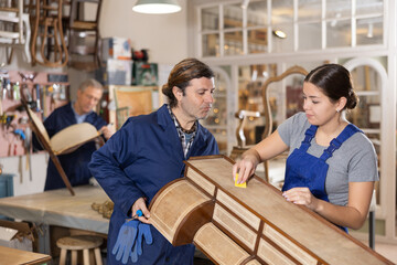 Man and woman are working on restoration of vintage chest of drawers together in a restoration workshop