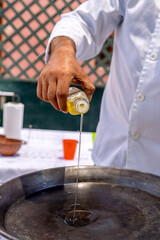 Chef pouring olive oil into paella pan for family meal