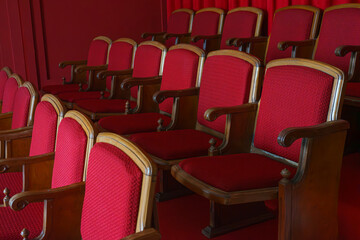 Fototapeta premium Empty rows of retro, old red theater or cinema seats. Old style, vintage chairs with red upholstery in concert hall.