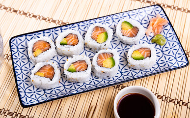 Set of fresh sushi rolls with salmon, avocado and sesame seeds served on plate. Japanese sushi uramaki or California roll.