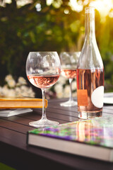Outdoor summer dining experience. Decorated open air party with rosé wine, fresh flowers and reading books.