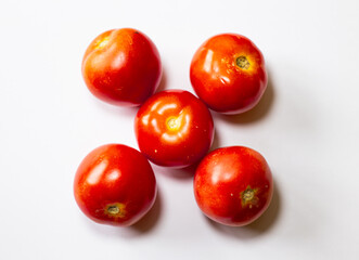 Five whole tomatoes, each with a distinct, slightly imperfect shape, arranged in a symmetrical pattern isolated on white background 
