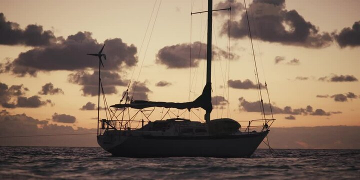contraluz de un velero al amanecer en el mar, desde la orilla,  silueta de un yate en el oc&eacute;ano al amanecer