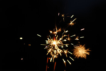 Obraz premium Sparkler is a type of handheld firework that burns slowly while emitting bright, colored sparks. It burns in high temperature over 1000 °