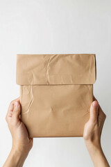 Fototapeta premium Close-up of hands holding a gluten-free food delivery package, with the contents peeking out, on a clean white background