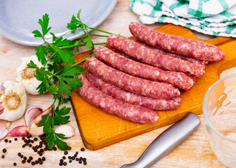 Traditional Catalan raw pork sausage longaniza ready for grilling on wooden board