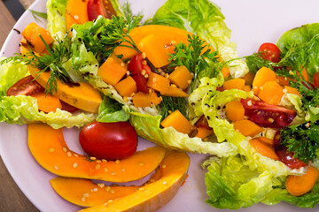Lettuce, pumpkin, cherry tomatoes, sesame put on a plate. Served with olive oil sauce, salt, pepper, lemon and pumpkin puree..
