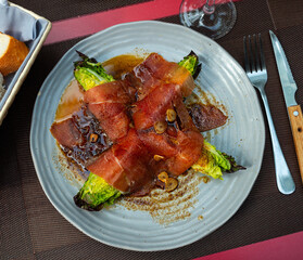 Delicious Spanish cabbage dish with bacon and sauce on a plate. Appetizing appetizer Cogollos con jamon