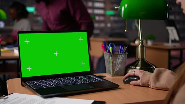 Young female student studies for her upcoming exams with green screen at the library, collecting academic information to use as citations for college paper. Bachelor degree research. Camera B.