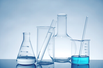 Laboratory glassware with liquid on mirror surface against light background