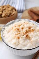 Tasty rice pudding with cinnamon served on white table, closeup