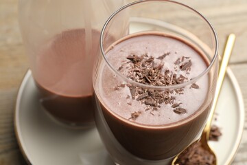 Tasty chocolate milk with shavings on wooden table, closeup