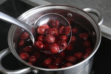 Making compot of cherries. Simmering fruits in pot on stove, closeup