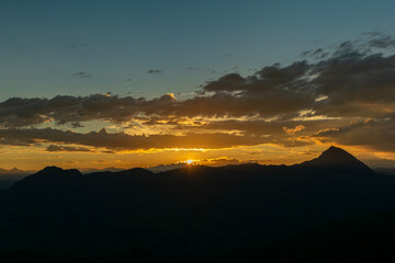 Dramatic mountain silhouette against a vibrant sunset sky with colorful clouds.