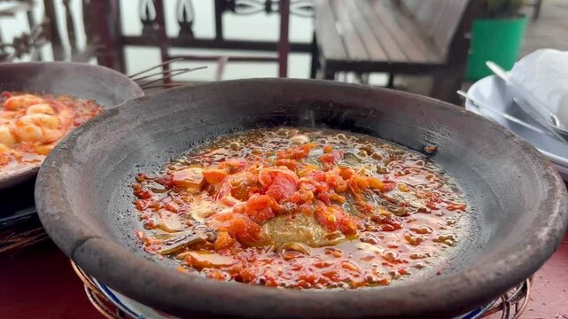 Pan-seared rabbitfish in spicy sambal served sizzling hot in a traditional clay mortar. Indonesian seafood cuisine captured fresh and vibrant.