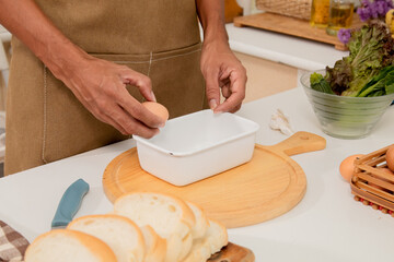 Asian man with beard sitting makes sandwich for breakfast in morning at kitchen. Male wear apron enjoy make food for health care in house,  free time in modern kitchen interior. healthy food at home.