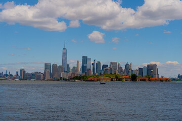 Obraz premium New York city. NYC cityscape. Lower Manhattan and One World Trade Center in New York Cit. Skyscrapers of Manhattan located near rippling water of New York bay against blue sky. New York skyscrapers.