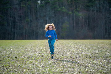 Child running on field. Happy kid running outdoors. Child jumping and running in nature. Child running in a meadow. Summer fun for active child. Playful kid freedom. Free childhood in nature.
