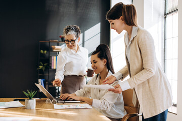 Businesswomen working together on laptop in modern office