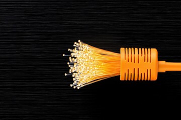 Abstract Orange Fiber Optic Cable with Golden Light Burst on Dark Background