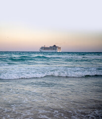 Fototapeta premium Cruise ship on the ocean. Luxury liner at ocean. Miami Beach with cruise ship. Turquoise water and cruise liner. Tourist cruise ship near the coast. Ocean waves and vessel boat.