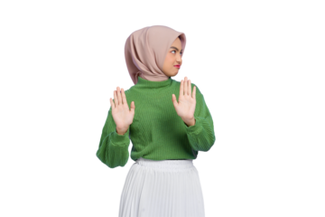 Beautiful annoyed Asian woman in green sweater makes stop gesture, demonstrates rejection isolated on transparent background
