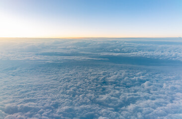 Beautiful orange and pink sunrise over the clouds, view from the plane.