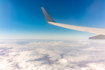 View from the airplane window at a beautiful cloudy sky and the airplane wing