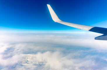 View from the airplane window at a beautiful cloudy sky and the airplane wing
