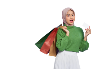 Shocked beautiful Asian woman in green sweater holding shopping bags and credit card isolated on transparent background