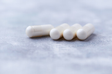Creatine capsules on bright wooden background. Soft focus. Close up. Copy space.