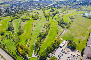 Fototapeta premium Golf course with a green grassy field and a parking lot with cars