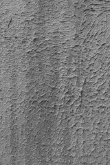 Vertical photo of grey rough plaster on a wall.