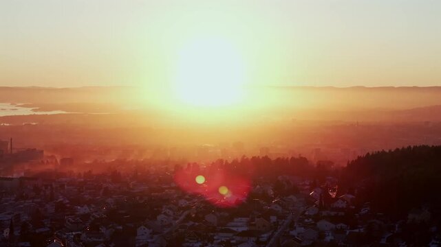 Artic winter vibrant sunset Olso Norway Norge aerial drone sun on horizon golden hour downtown Oslofjord city view Holmenkollen Holmenkollbakken Ski Jump Skimore Skisenter home buildings circle right